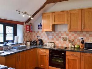 een keuken met houten kasten en een spoelbak bij Garden Cottage - Cp28 in Halwell