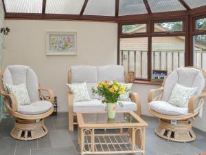 een veranda met 2 stoelen en een tafel met een vaas met bloemen bij Garden Cottage - Cp28 in Halwell