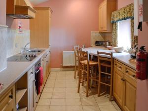 a kitchen with wooden cabinets and a counter top at The Old Stables in Uldale