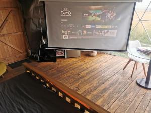 a large screen tv sitting on top of a wooden floor at Dome One with Hot Tub, Lincoln, Projector, Firepit in Lincoln