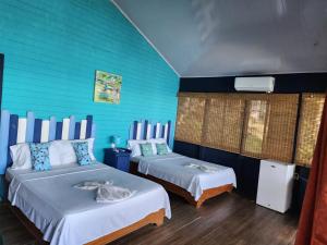 a bedroom with two beds and a blue wall at Cabinas La Parcela in Dominicalito