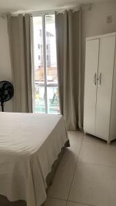 a bedroom with a bed and a large window at Apartamento refúgio tropical in Arraial do Cabo