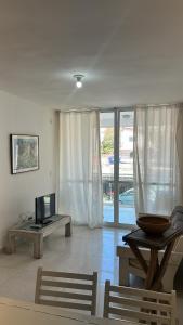 a living room with a television and a table and a couch at Apartamento refúgio tropical in Arraial do Cabo