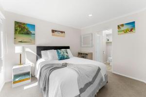 a white bedroom with a large white bed in it at Town & Surf Retreat - Mount Maunganui in Mount Maunganui