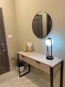 a table with a lamp and a mirror on the wall at Cosy, accessible, comme et sécure in Kinshasa