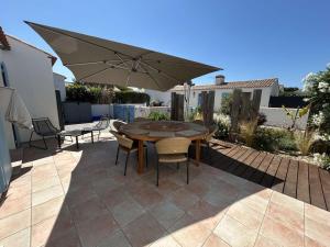 une table et des chaises avec un parasol sur une terrasse dans l'établissement Charmante Maison 3 pièces à 400m de la plage, L'Herbaudière - FR-1-224B-248, à Noirmoutier-en-l'lle 7 autres photos