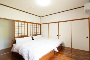 今帰仁村にあるOcean View House Nakijinのベッドルーム(ガラスドア付きの大きな白いベッド付)