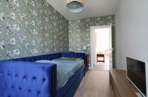 un divano blu in una camera da letto con carta da parati floreale di Le Gentiane - Villa Chanterive a La Bourboule