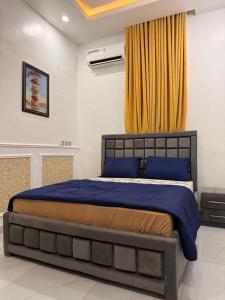 a bedroom with a bed with blue sheets and a yellow curtain at Beautifully furnished 4 Bedroom Duplex in Lekki