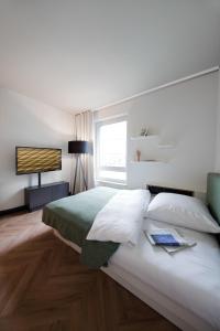 a white bedroom with a bed and a window at SMARTments business München Parkstadt Schwabing in Munich