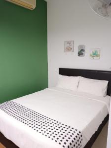 Un dormitorio con una cama blanca con una pared verde. en Langkawi Western Motel, en Pantai Cenang