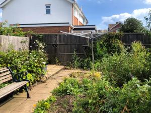 a garden with a bench in front of a fence at Seashells in Lowestoft