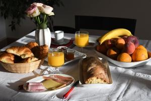 ein Tisch mit einem Frühstück aus Brot, Obst und Orangensaft in der Unterkunft Le Cercle Chambres climatisées in Coligny