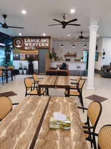 Un restaurante con mesas y sillas en una sala. en Langkawi Western Motel, en Pantai Cenang