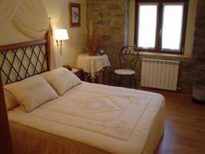 Cette chambre comprend un grand lit blanc et une table. dans l'établissement Hostal Restaurante Arangoiti, à Yesa