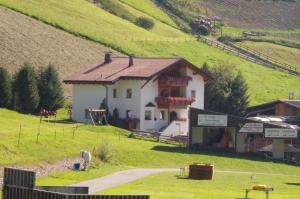 ein kleines weißes Haus auf einem Hügel neben einem Feld in der Unterkunft Wastlhof in Mals im Vinschgau