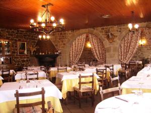 un restaurant avec des tables et des chaises blanches et un lustre dans l'établissement Hostal Restaurante Arangoiti, à Yesa