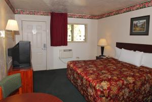 a hotel room with a bed and a tv at Stone Inn Extended Stay U of A in Tucson