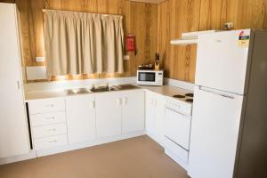 une cuisine avec des armoires blanches et un réfrigérateur blanc dans l'établissement Birdsville Tourist Park, à Birdsville 34 autres photos
