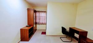 Una habitación con una silla y un escritorio y una ventana. en Aathidya Lodge, en Ādoni