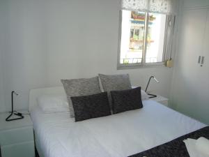 a bedroom with a white bed with pillows and a window at El HECHIZO in Seville