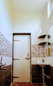 baño con puerta blanca y lavamanos en Aathidya Lodge, en Ādoni