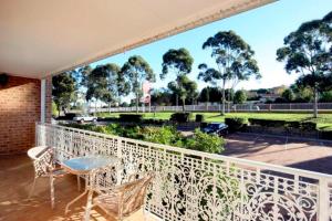 uma varanda com mesa, cadeiras e árvores em The Hermitage Motel - Campbelltown em Campbelltown