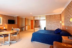 The Hermitage Motel - Campbelltown في كامبلتاون: غرفة نوم بسرير ازرق وغرفة معيشة