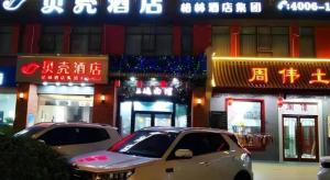 two cars parked in front of a building with neon signs at Shell Hotel Yancheng Binhai County Renmin Nan Road in Binhai