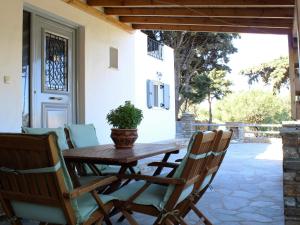 een houten tafel en stoelen op een patio met een potplant bij Villa Nefeli in Batsi