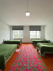 a room with green beds and a red carpet at Коломто in Bokonbayevo