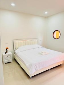 a white bedroom with a large bed and a table at Fandee suites in Ban Sa Kut