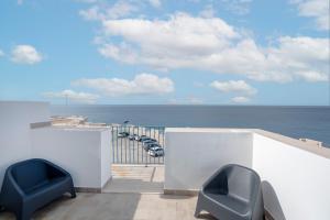 two blue chairs sitting on a balcony overlooking the ocean at Mare | Fronte Mare con Balcone – Vicino al Centro Storico in Polignano a Mare