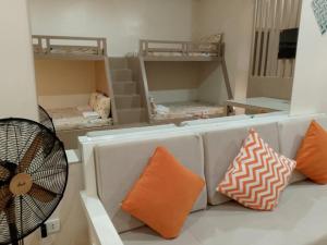 a room with a couch with pillows and a fan at PMPJ Cabin in Lipa +2 photos
