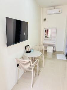 a room with a table and chairs and a tv on the wall at Fandee suites in Ban Sa Kut