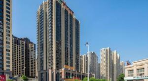 a tall building in a city with tall buildings at Vienna Hotel Fuzhou Changle Shouzhan Hangcheng Metro Station in Fuzhou