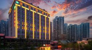 a large building with lights on it in a city at Vienna Hotel Jinan Railway Station in Jinan
