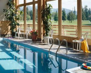 a house with a swimming pool with chairs and windows at Grouse Mountain Lodge in Whitefish