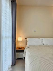 a bedroom with a bed and a table with a lamp at Hatyai Luxe Stay in Hat Yai