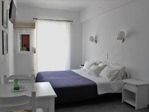 a white bedroom with a bed and a table at Villa Nefeli in Batsi