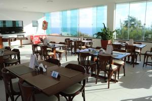 a restaurant with tables and chairs and large windows at Pousada Mar Aberto in Beberibe