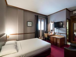 a bedroom with a bed and a desk and a television at Four Chain View Hotel in Singapore