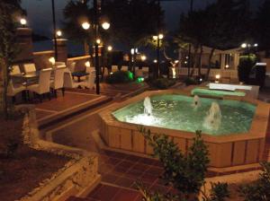 a swimming pool with two water fountains at night at Yona Motel in Çeşme