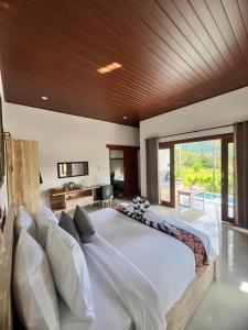 a large bedroom with a large bed with white pillows at Dewi Teduh Villa in Sidemen +86 photos