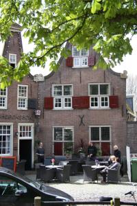 people sitting at tables in front of a building at 't Koetshuys in Heenvliet