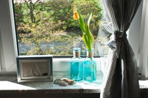 una ventana con dos botellas y un jarrón con una flor en Morski Sen, en Gdansk