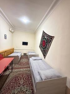 a room with three beds and a tv on the wall at Avenue Guest House in Samarkand