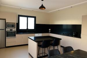 a kitchen with a black counter and stools in it at Villa moderne avec grande piscine sans vis-à-vis Berkane Saïdia in Berkawe