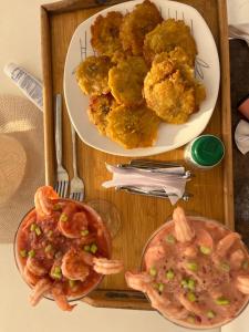a wooden tray with two plates of food and shrimp at Roma beach in Cartagena de Indias