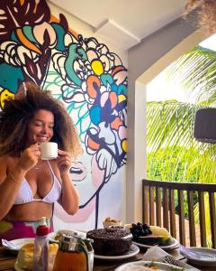 a woman in a bikini holding a cup of coffee at Pousada Unaí in Porto De Galinhas